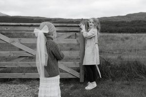 A black and white photo collage showing people sitting and interacting on a wooden fence in a rural landscape.