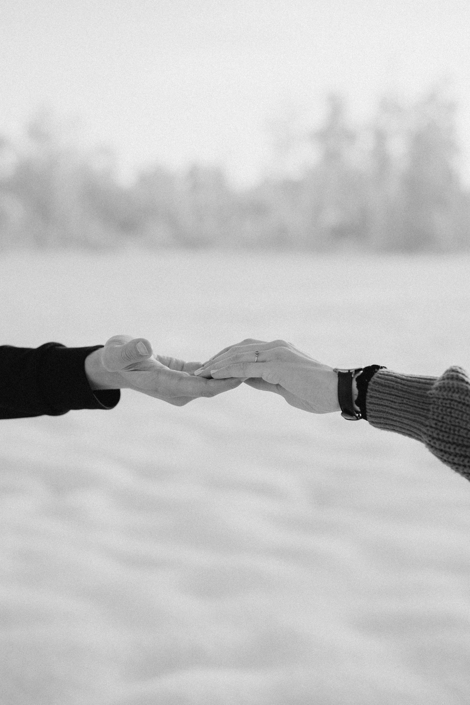 Two hands reaching towards each other against a snowy white background.