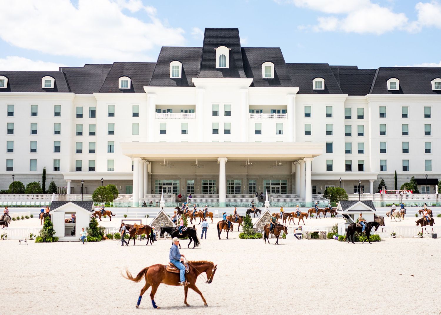 Large white equestrian facility with multiple buildings and riding arena.