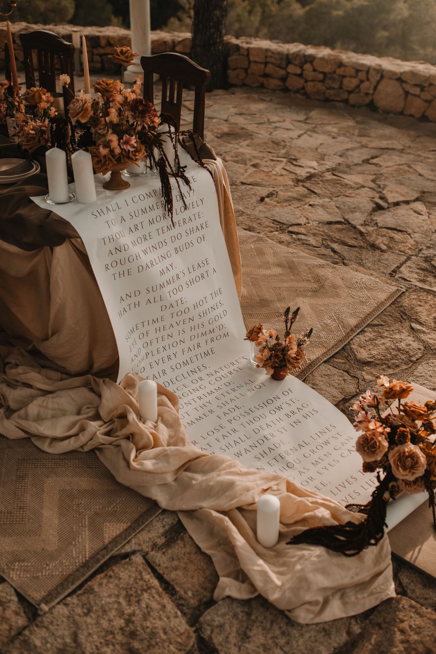 A series of vintage-style wedding vows written on white fabric displayed on stone flooring with dried autumn flowers.
