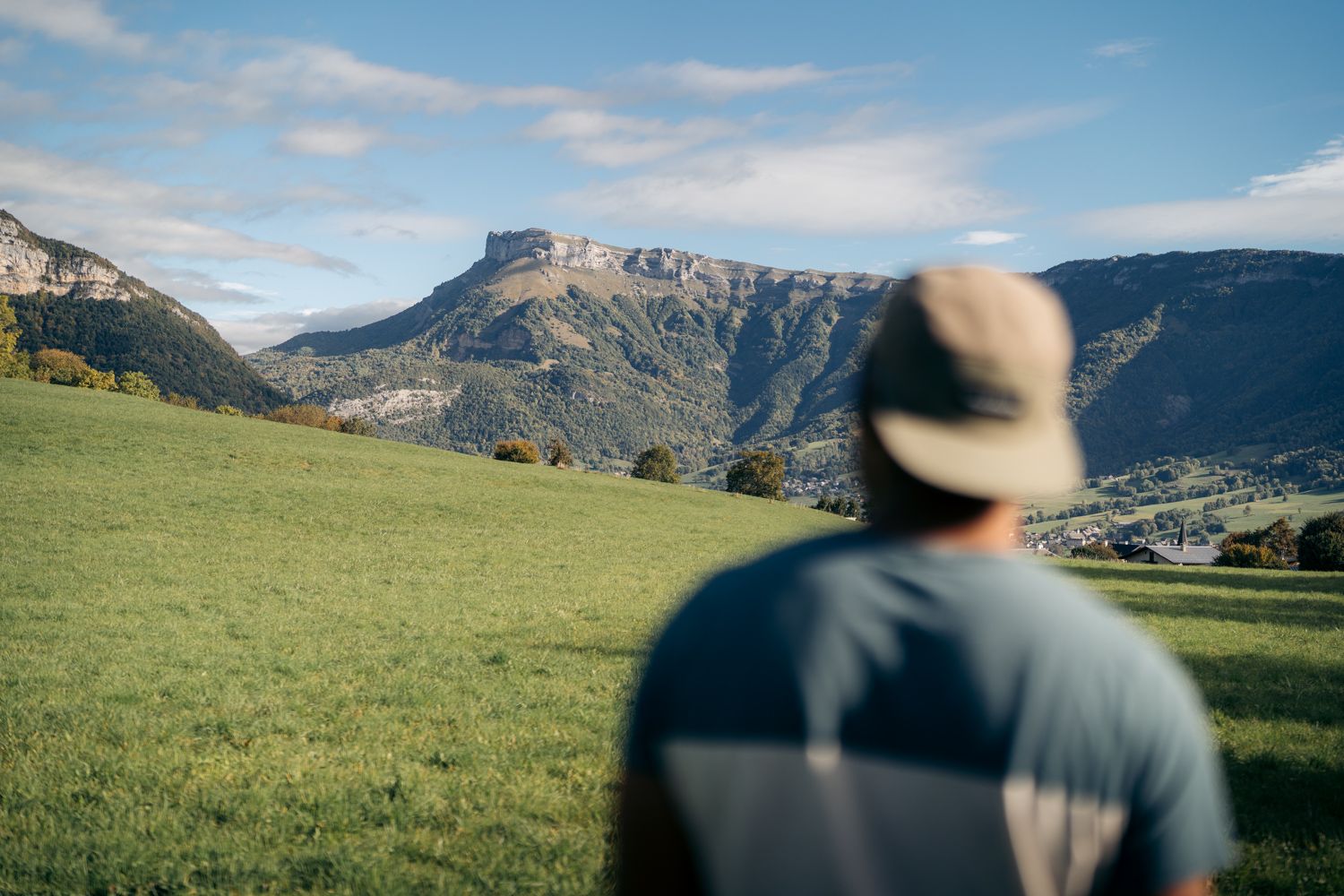 Un randonneur en premier-plan regarde le massif des bauges au loin depuis Curienne