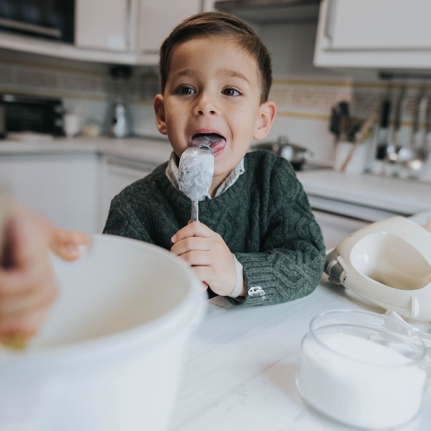 A child enjoying a sweet treat while sitting at a white kitchen counter with a glass of milk.