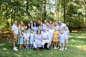 A group wearing coordinated blue and yellow outfits poses together for outdoor family photos in a sunny wooded setting.