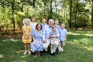 Family members in matching light blue and yellow attire gather for portraits in a green park setting.