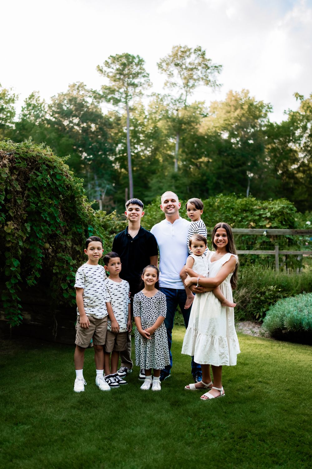 A family group poses together on a green lawn during a summer evening photoshoot.