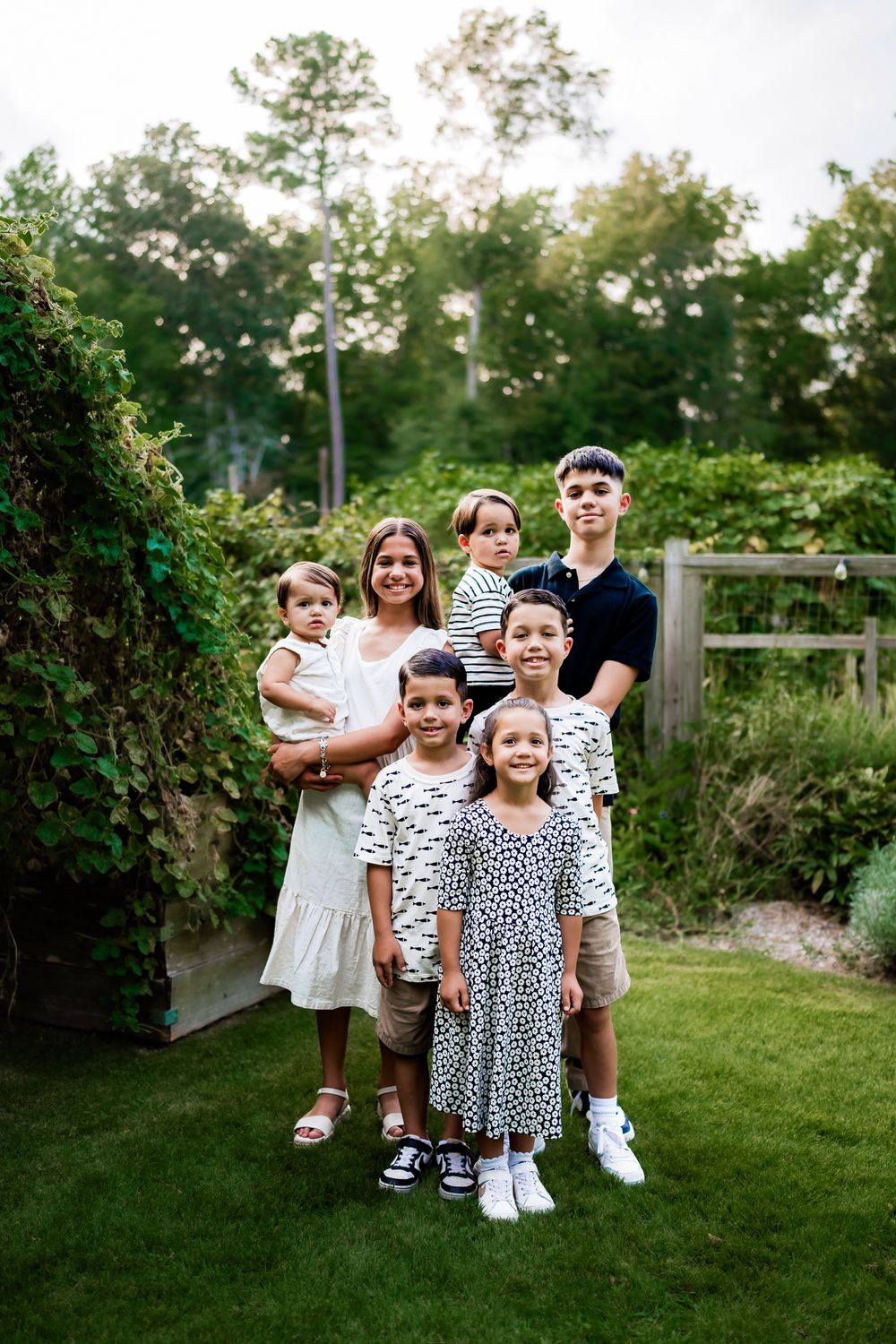 A group poses together on a grassy lawn during a summer evening photoshoot.