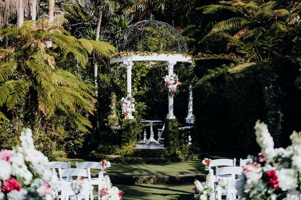 Elegant outdoor wedding ceremony setup with white gazebo and floral decorations.