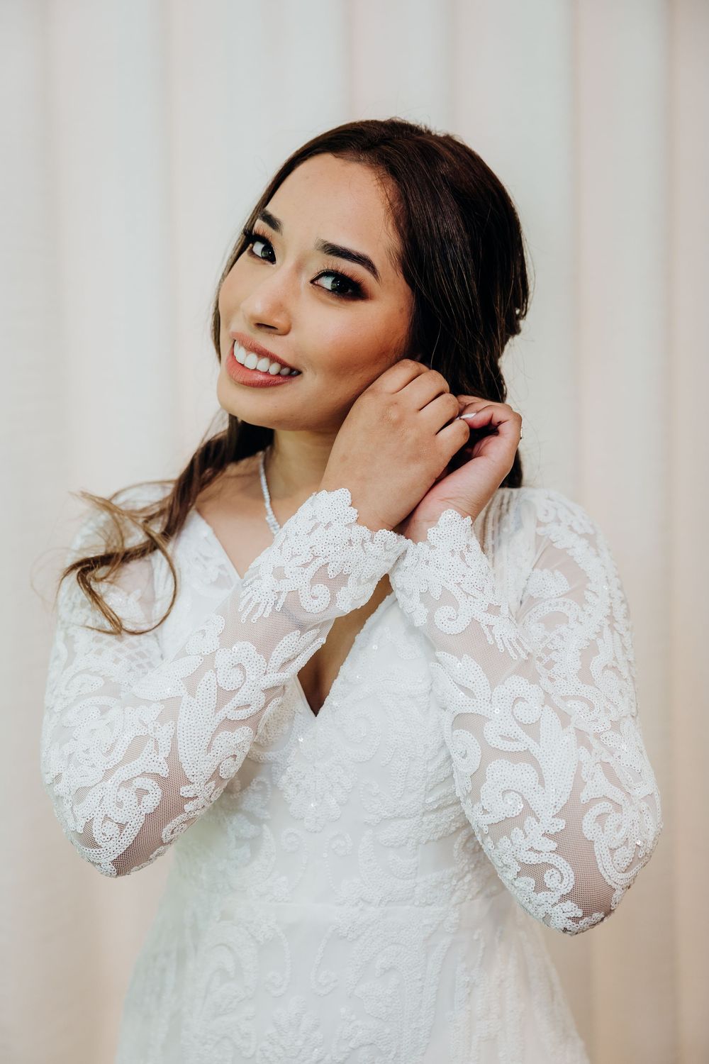 Close-up portrait shots of a bride in an elegant white lace wedding dress with long sleeves.