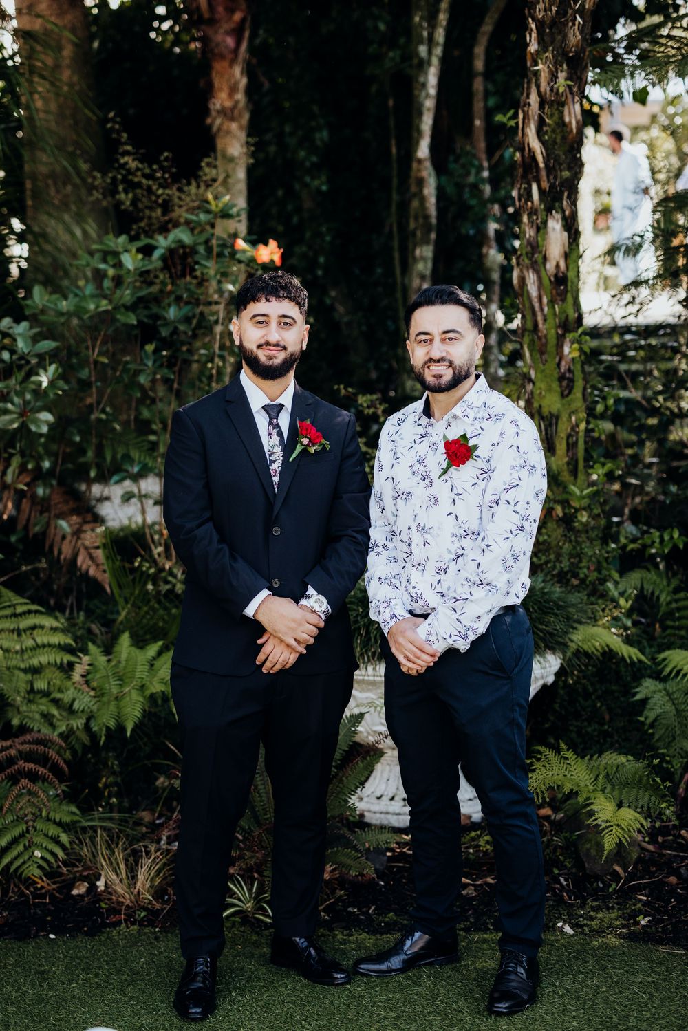 Wedding party members in formal attire posing together in a lush garden setting.