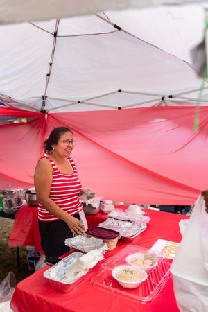 Vendor booth with red and white striped theme displaying food items under a white tent.