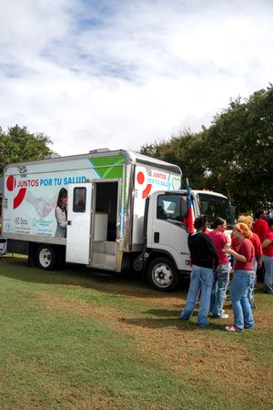Mobile health clinic vans parked on grassy field providing medical services to community members.