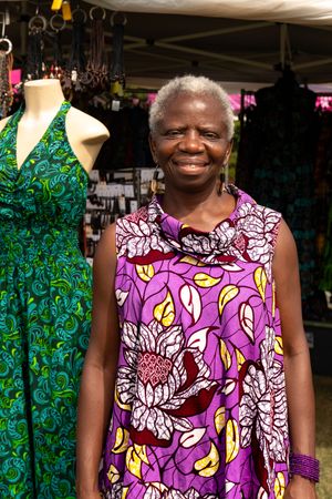 Colorful African print dresses on display with vibrant purple floral and green patterns at a market stall.