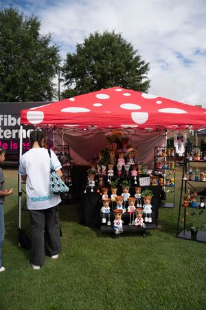 Red and white polka dot tent canopy set up at an outdoor craft fair with vendor displays.