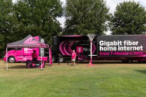 Row of pink T-Mobile branded vehicles and tents set up in a grassy field for an outdoor event.