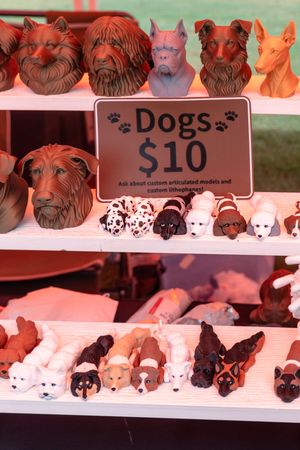 Display of decorative ceramic dog figurines priced at $10 at a craft fair booth.