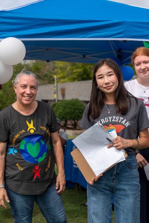 Group wearing matching t-shirts with colorful designs at an outdoor gathering.