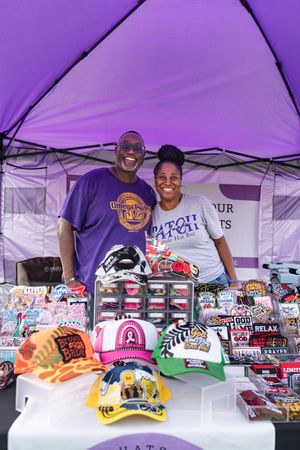 Merchandise display under a purple tent with various branded items and apparel.