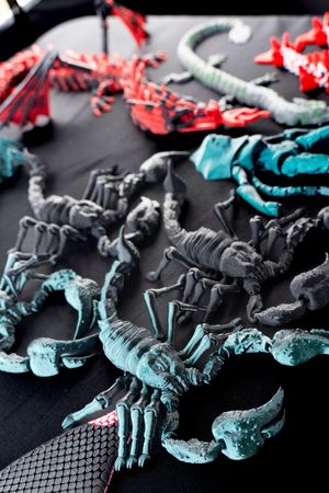 Display of colorful ceramic or clay shoes arranged on a black surface in teal and red tones.