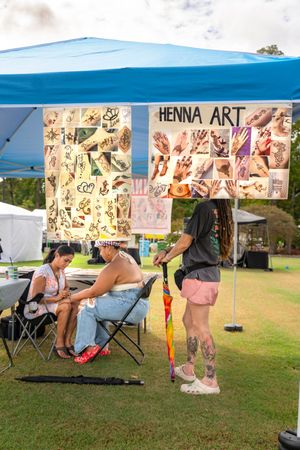 Henna art booth setup at an outdoor festival with chairs and display materials.