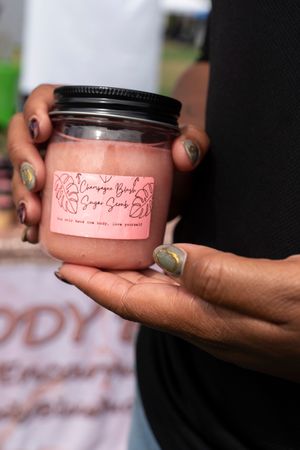 Hands holding pink beauty product jars with black lids.