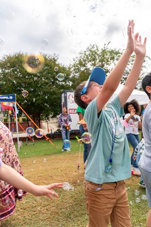 People playing with soap bubbles at an outdoor festival event.