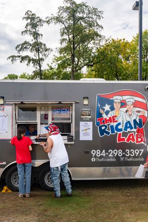 Food truck serving Puerto Rican cuisine with customers ordering at the window.