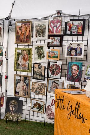 Art gallery display with photographs and artwork mounted on wire grid panels with orange signage.