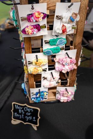 Wooden display rack with colorful hair accessories and small chalkboard signs.
