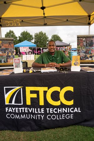 Fayetteville Technical Community College banner display at outdoor event under yellow tent.