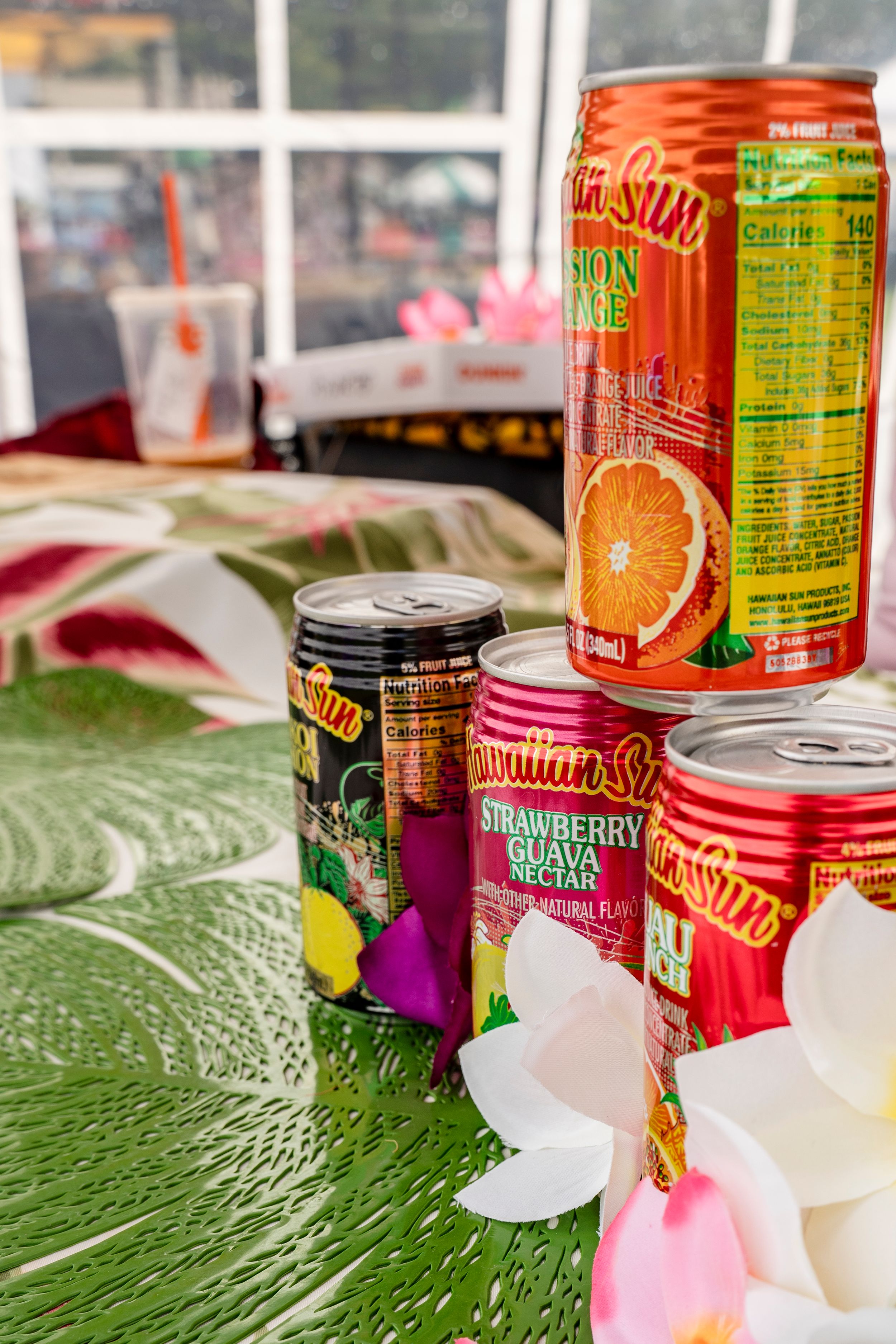 Colorful canned beverages and white decorative elements displayed on a green textured surface.