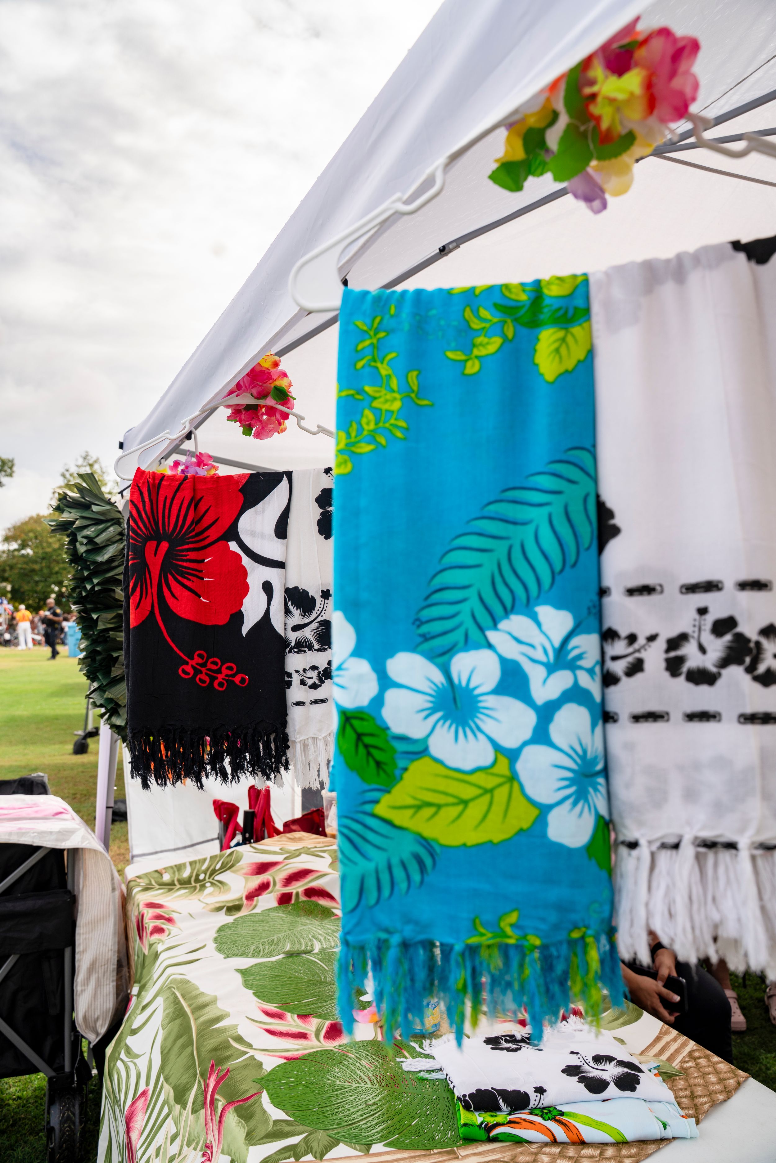 Colorful tropical floral print banners with hibiscus flowers hanging at outdoor event.