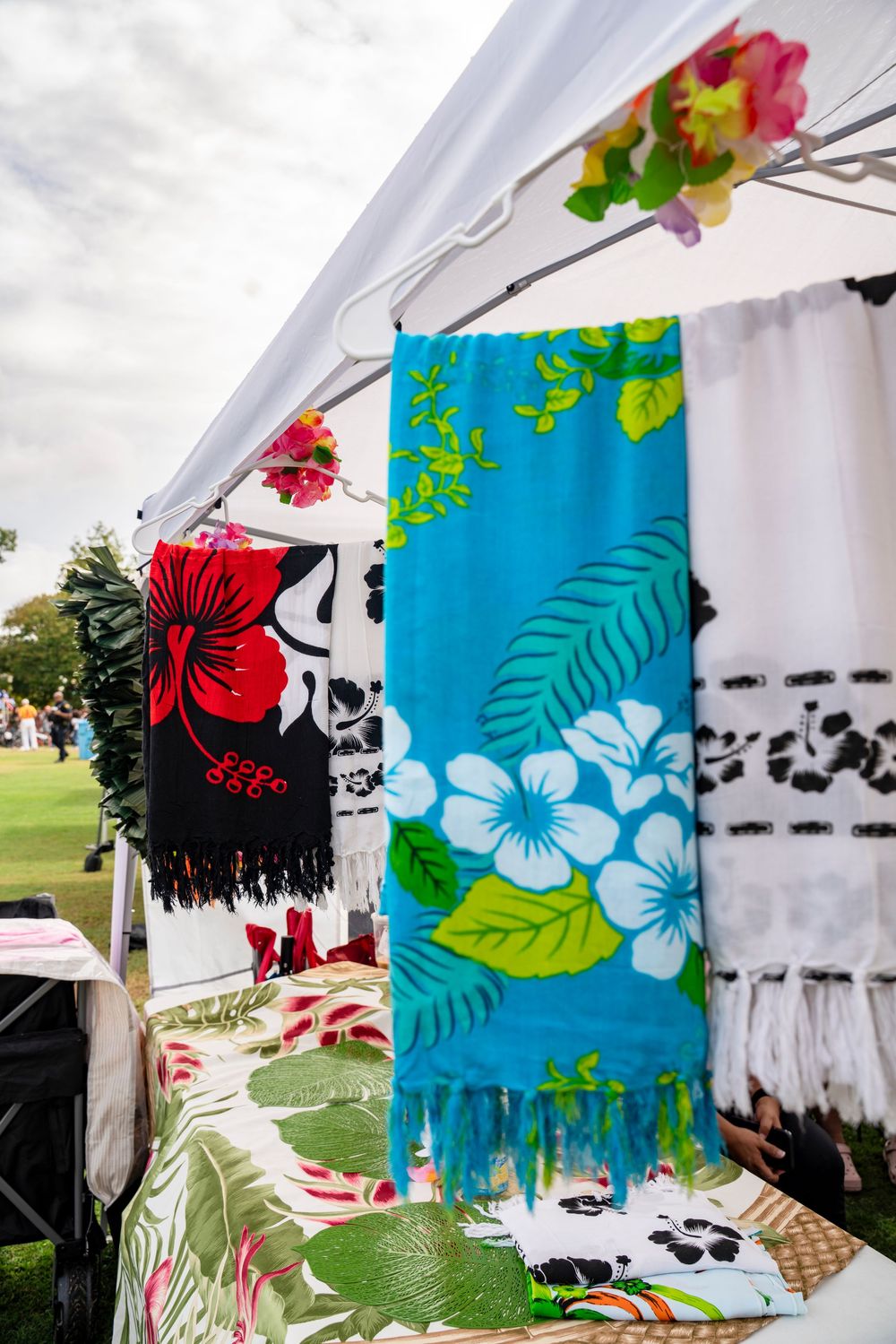 Colorful tropical floral print banners with hibiscus flowers hanging at outdoor event.