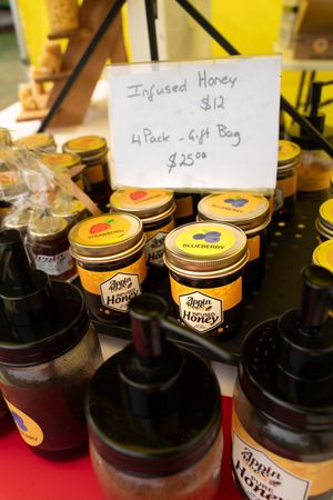 Display of honey jars with price tags and labels arranged on a retail counter.