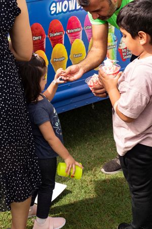 Snow cone stand with colorful syrup bottles serving refreshments at an outdoor event.