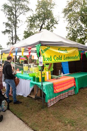 Outdoor vendor booth with colorful tent selling iced cold lemonade at a festival.