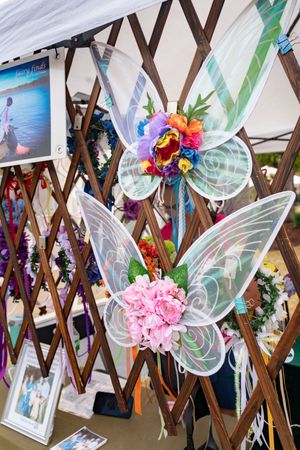 Decorative fairy wings and colorful flowers displayed on wooden lattice wall.