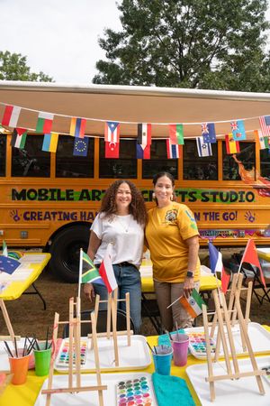 Mobile art studio tent with colorful international flags and art supplies set up outdoors.