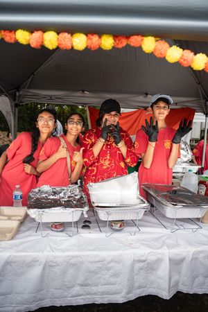 Food service workers in red uniforms standing behind buffet tables with paper lantern decorations overhead.