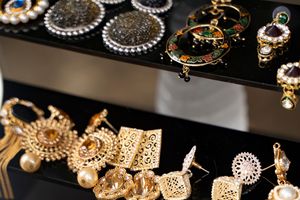 Display of ornate gold and pearl jewelry pieces against black background.