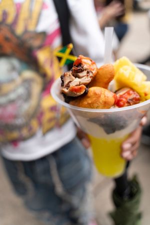 Close-up shots of festival food being served in paper boats with colorful garnishes and toppings.
