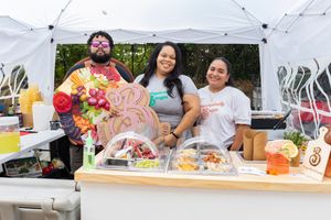 Vendors displaying colorful food and drinks at their festival booth.