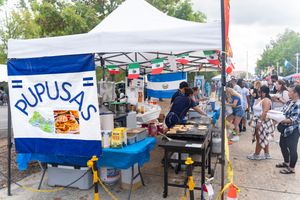 Outdoor festival setup with white tents and vendor booths along a street.