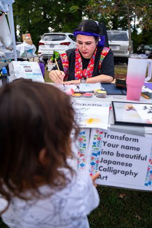 Japanese calligraphy art booth at a cultural festival offers personalized name translations.