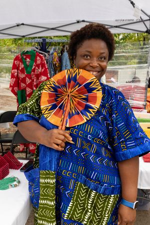 Colorful display at a market stall featuring vibrant African print clothing and a circular fan decoration.