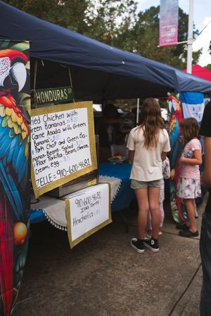 Outdoor market stalls with handwritten signs and colorful banners displaying cultural items.