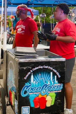 Vendors operating a Coco Fresco beverage stand at an outdoor festival.