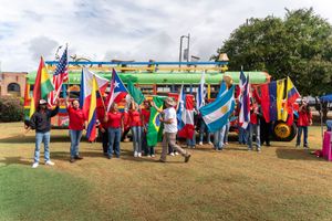 Row of colorful festival flags and banners displayed outdoors on a grassy field.