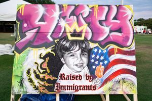 A series of colorful graffiti murals on walls featuring American flag imagery and text about immigrants.