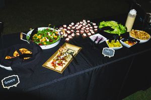 Buffet spread of appetizers and finger foods displayed on black tablecloth.