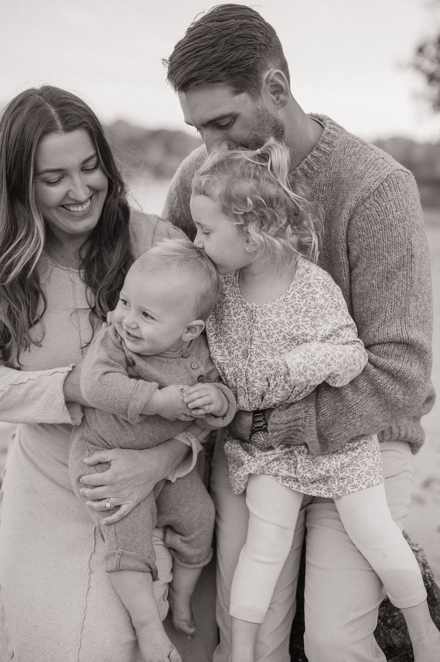 Black and white family portrait series showing tender moments and embraces on the beach.